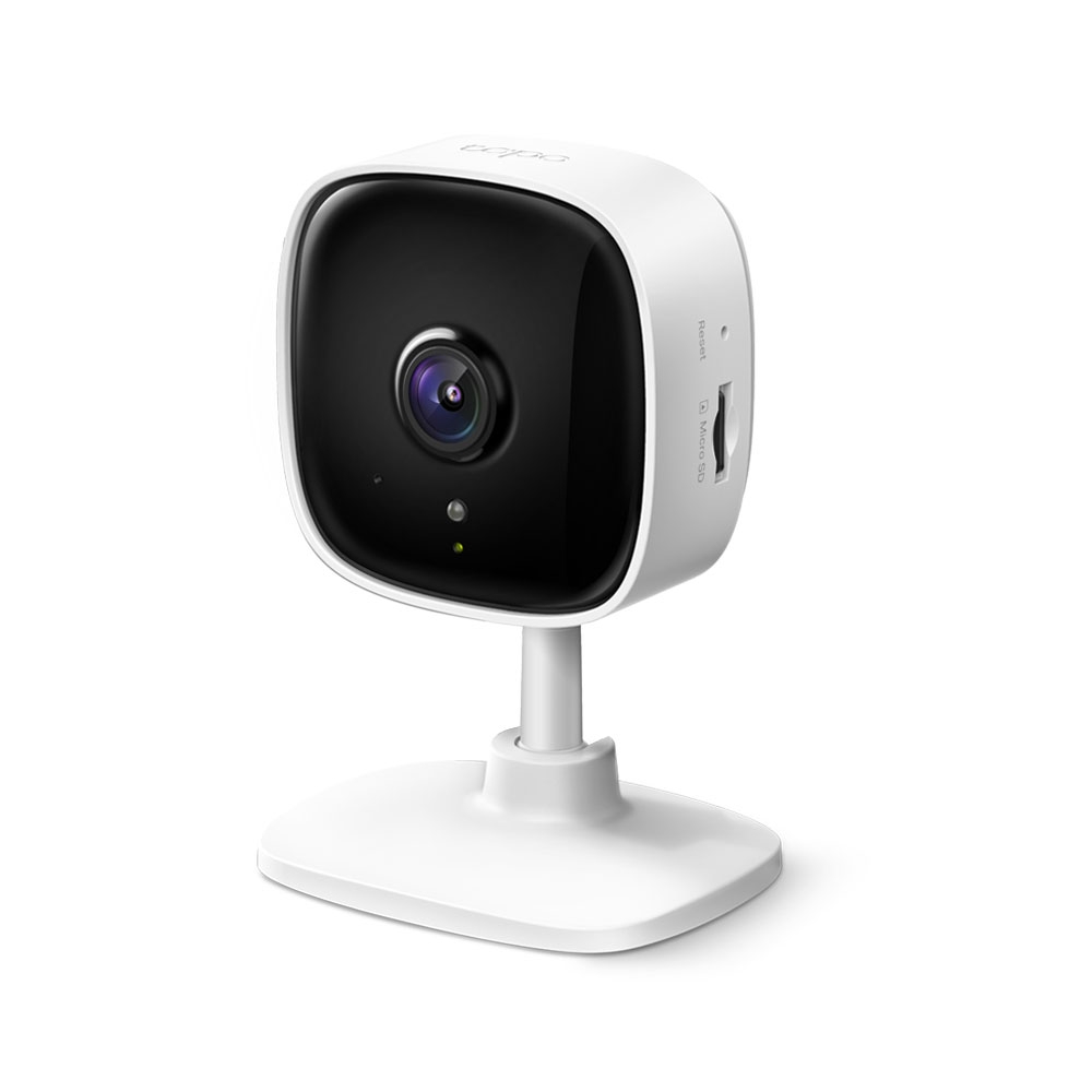 Câmera TP-Link Tapo C100 branca, compacta, instalada sobre uma mesa dentro de um ambiente residencial.